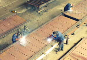 Three welders working on large metal structures, view from above